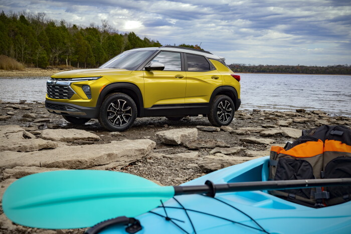 Front 7/8 view of 2024 Chevrolet Trailblazer ACTIV in Copper Harbor Metallic parked next to a canoe by a lake. Preproduction model shown. Actual production model may vary. Available in fall 2023.
