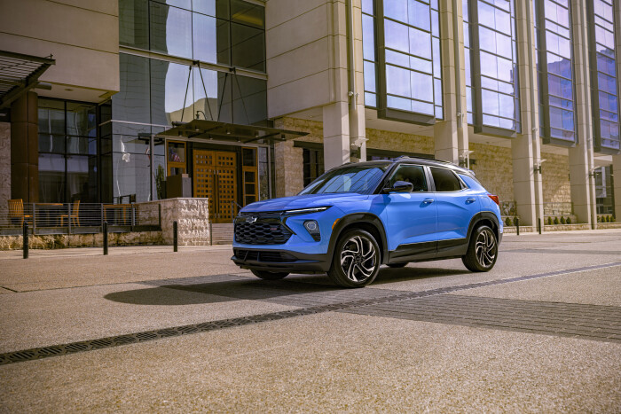 Drivers side front 3/4 view of 2024 Chevrolet Trailblazer RS in Fountain Blue driving past a building. Preproduction model shown. Actual production model may vary. Available in fall 2023.